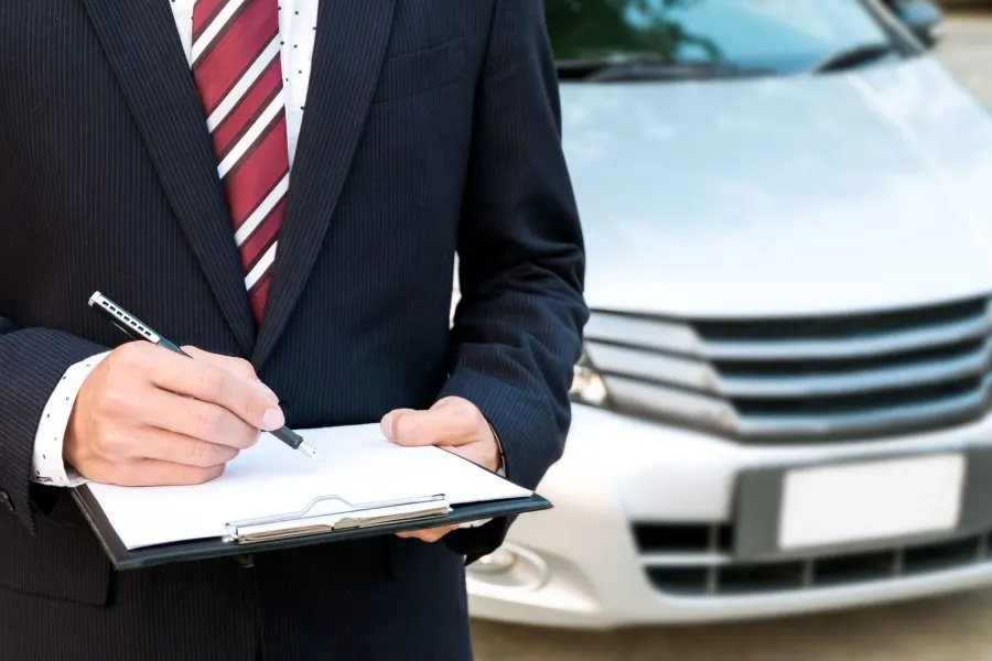 Agent with clipboard beside a car